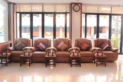 a brown leather couch in a room with windows at Lub Sbuy House Hotel - SHA in Phuket Town