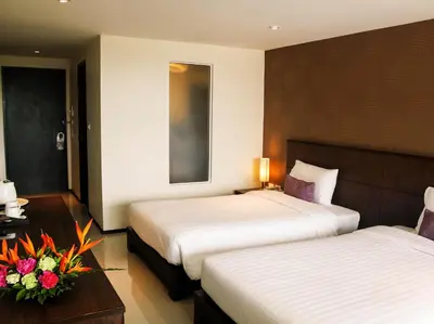 a hotel room with two beds and a table with flowers at Lub Sbuy House Hotel - SHA in Phuket Town