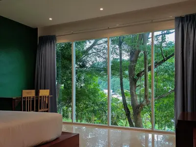 a bedroom with a large window with a tree outside at Phi Phi Chang Grand Resort in Phi Phi Don