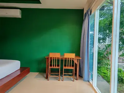 a table and two chairs in a room with a green wall at Phi Phi Chang Grand Resort in Phi Phi Don