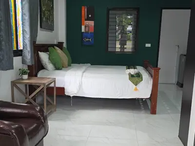 a bedroom with a white bed with a green wall at Marin' s Home in Thalang