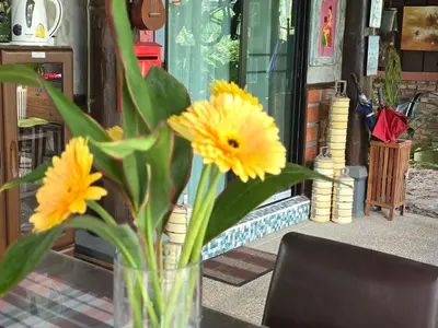 a vase filled with yellow flowers sitting on a table at Marin' s Home in Thalang