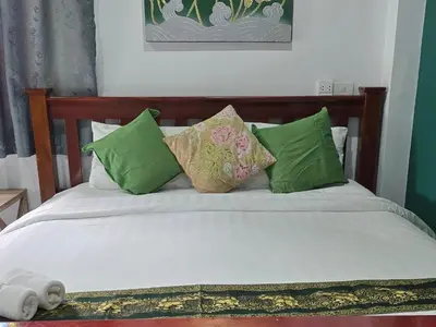 a bed with green and white pillows on it at Marin' s Home in Thalang