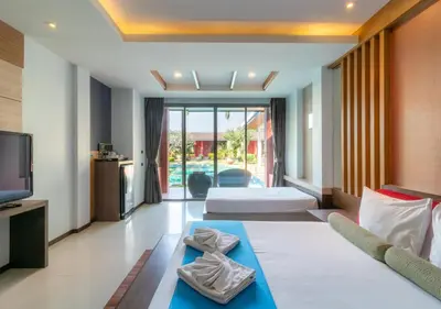 a living room with two beds and a television at Mai Morn Resort SHA Plus in Phuket Town