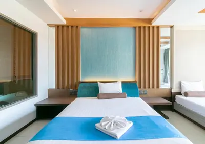 a bedroom with a blue and white bed and a window at Mai Morn Resort SHA Plus in Phuket Town