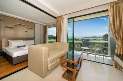 a bedroom with a bed and a chair and a balcony at Panora sea view -modern facilities walk to beach in Surin Beach