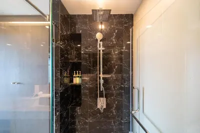 a bathroom with a shower with black tiles at Panora sea view -modern facilities walk to beach in Surin Beach