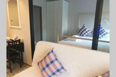 a room with a bed with a mirror and a couch at Title Residence Naiyang Beach Phuket in Nai Yang Beach