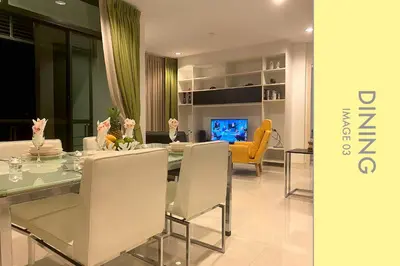 a woman sitting at a dining table in a living room at Stylish Condo w. Pool View 2F in Kamala Beach