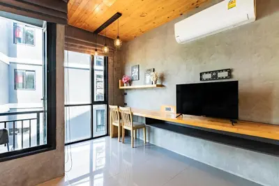 a living room with a table and a television on a wall at Relife The Windy by VillaCarte in Rawai Beach