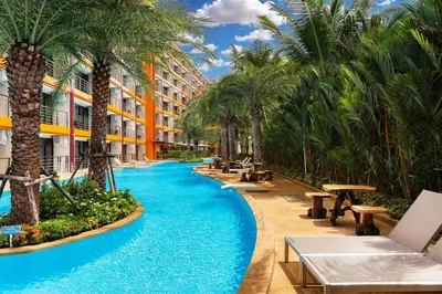 a swimming pool with palm trees in a resort at Mai Khao Beach Condo by VillaCarte in Mai Khao Beach