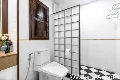 a bathroom with a toilet and a tiled wall at Patong Tower Sea View by PHR in Patong Beach
