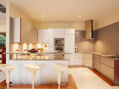a large kitchen with white cabinets and white stools at Laguna Waters in Phuket Town