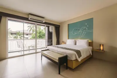 a bedroom with a large bed and a balcony at TIRAS Patong Beach Hotel in Patong Beach