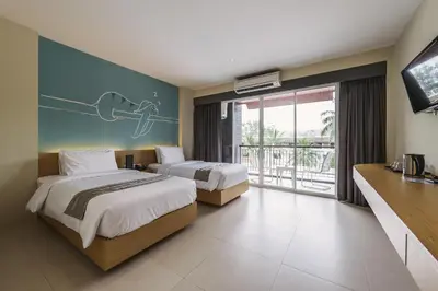 a hotel room with two beds and a television at TIRAS Patong Beach Hotel in Patong Beach