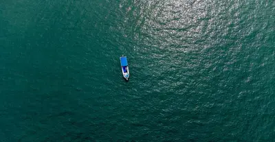 a small boat in the middle of the water at Hillhouse - Koh Yao Noi in Ko Yao Noi
