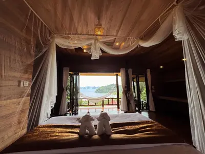 two stuffed elephants sitting on a bed in a bedroom at Hillhouse - Koh Yao Noi in Ko Yao Noi