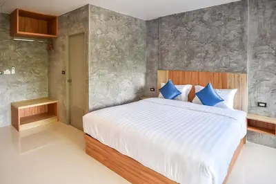 a bedroom with a large bed with blue pillows at Dee Homestay in Ban Pa Khlok