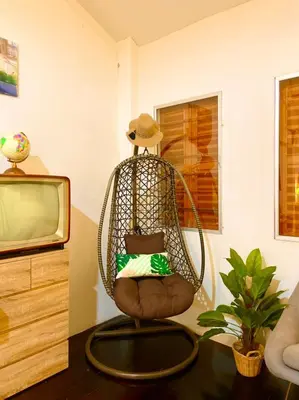 a rattan chair with a hat sitting next to a tv at Primego Boutique Hotel in Phuket Town