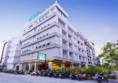 a large white building with motorcycles parked in front of it at Garden Phuket Hotel in Patong Beach