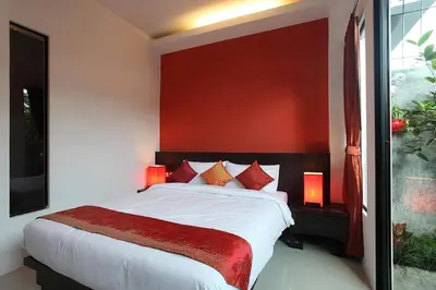 a bedroom with a large bed with a red wall at KARON SINO House in Karon Beach