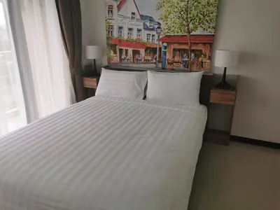 a bed with white sheets and pillows in a bedroom at APARTMENTS MBC in Mai Khao Beach