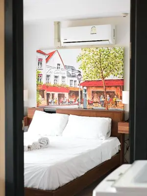 a bed in a room with a picture of a street at APARTMENTS MBC in Mai Khao Beach