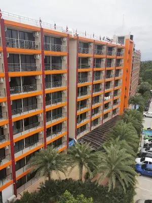an orange apartment building with palm trees in front of it at APARTMENTS MBC in Mai Khao Beach