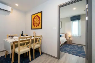 a dining room with a table and a bedroom at Luxury Apartment at Title Residencies Naiyang Beach in Phuket Town