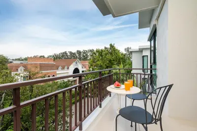 a balcony with two chairs and a table with fruit on it at The Title Rawai Beach West Wing in Phuket Town