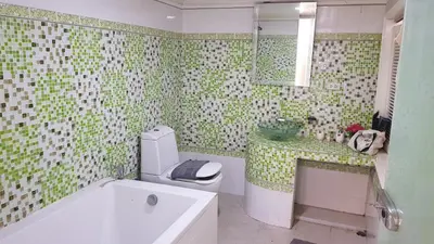 a bathroom with a green and white tiled wall at Kata Happy Place in Kata Beach