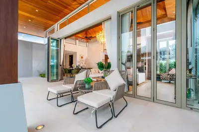 an indoor patio with white chairs and a table at Botanica Bangtao Beach Villa in Phuket Town