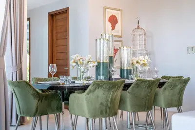 a dining room with a table and green chairs at Botanica Bangtao Beach Villa in Phuket Town