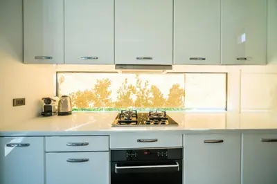 a kitchen with white cabinets and a stove top oven at Cocoon Villa - Peaceful private pool villa in north Phuket in Phuket Town
