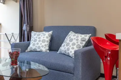 a blue couch with pillows and a glass table at LUMA Condo 1BR Open View NBC Nai Harn in Rawai Beach