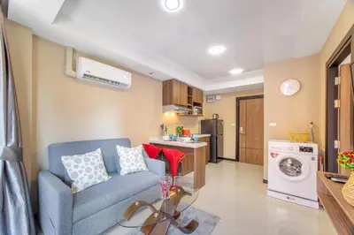 a living room with a blue couch and a kitchen at LUMA Condo 1BR Open View NBC Nai Harn in Rawai Beach