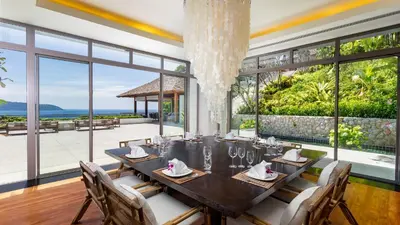a dining room with a table and chairs and large windows at Villa Chelay in Kamala Beach