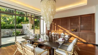 a dining room with a table and chairs and a chandelier at Villa Chelay in Kamala Beach