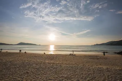 a group of people on the beach at sunset at Magnific Patong in Patong Beach