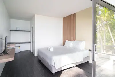 a bedroom with a white bed and a sliding glass door at Pine Bungalow Krabi in Klong Muang Beach