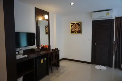 a room with a desk with a television and a mirror at Patong Mansion - SHA Certified in Patong Beach