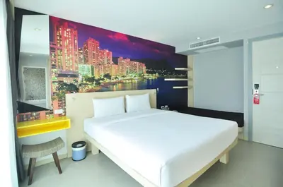 a bedroom with a large white bed and a painting at The AIM Patong Hotel in Patong Beach