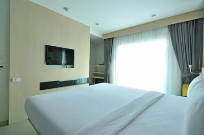 a bedroom with a large white bed and a window at The AIM Patong Hotel in Patong Beach