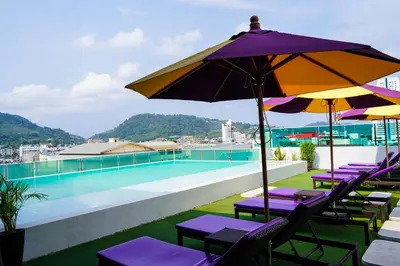 a group of chairs with umbrellas next to a swimming pool at The AIM Patong Hotel in Patong Beach