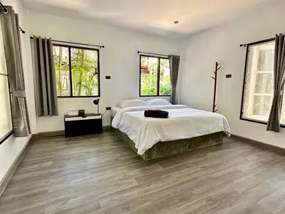 a bedroom with a large bed and two windows at Sand Beach Bungalow in Klong Muang Beach