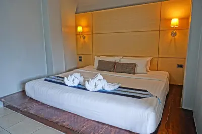 a bedroom with a large white bed with towels on it at Montree Phuket Hotel in Phuket Town