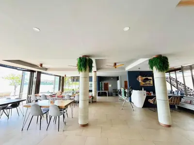 a dining room with tables and chairs and palm trees at Charcoal Panwa Beach Phuket in Ban Tha Khreng