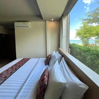 a bedroom with a bed with pillows and a window at Charcoal Panwa Beach Phuket in Ban Tha Khreng