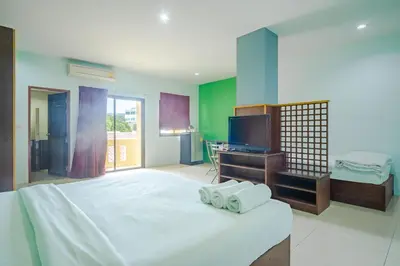a bedroom with a large white bed and a television at AJ Residence in Phuket Town