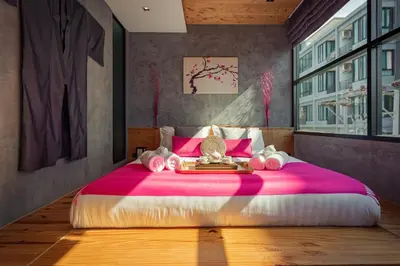a bedroom with a large pink bed with pink sheets at Cozy design studio near Nai Harn beach in Nai Harn Beach